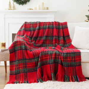 Un plaid tartan écossais à franges drapé sur un canapé clair dans un salon lumineux, avec un motif à carreaux traditionnel et des franges visibles sur le bord du textile.