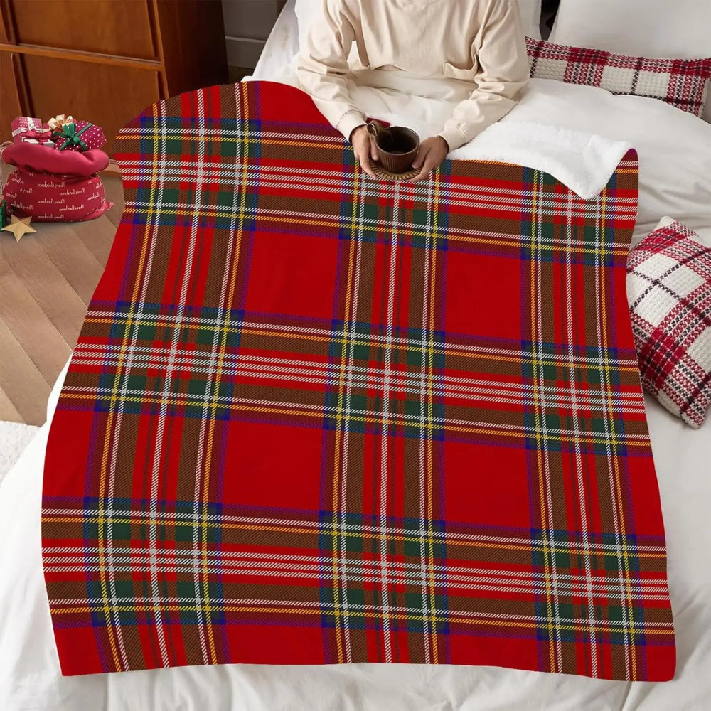Un plaid tartan style écossais étendu sur un lit dans une chambre chaleureuse, avec une personne assise tenant une tasse, créant une atmosphère cosy et hivernale.