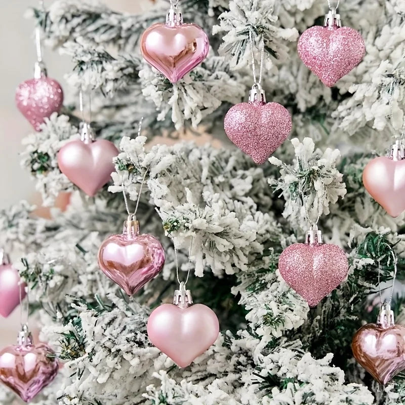 Lot de douze boules de Noël roses à finitions brillantes posées sur fond blanc avec rubans festifs