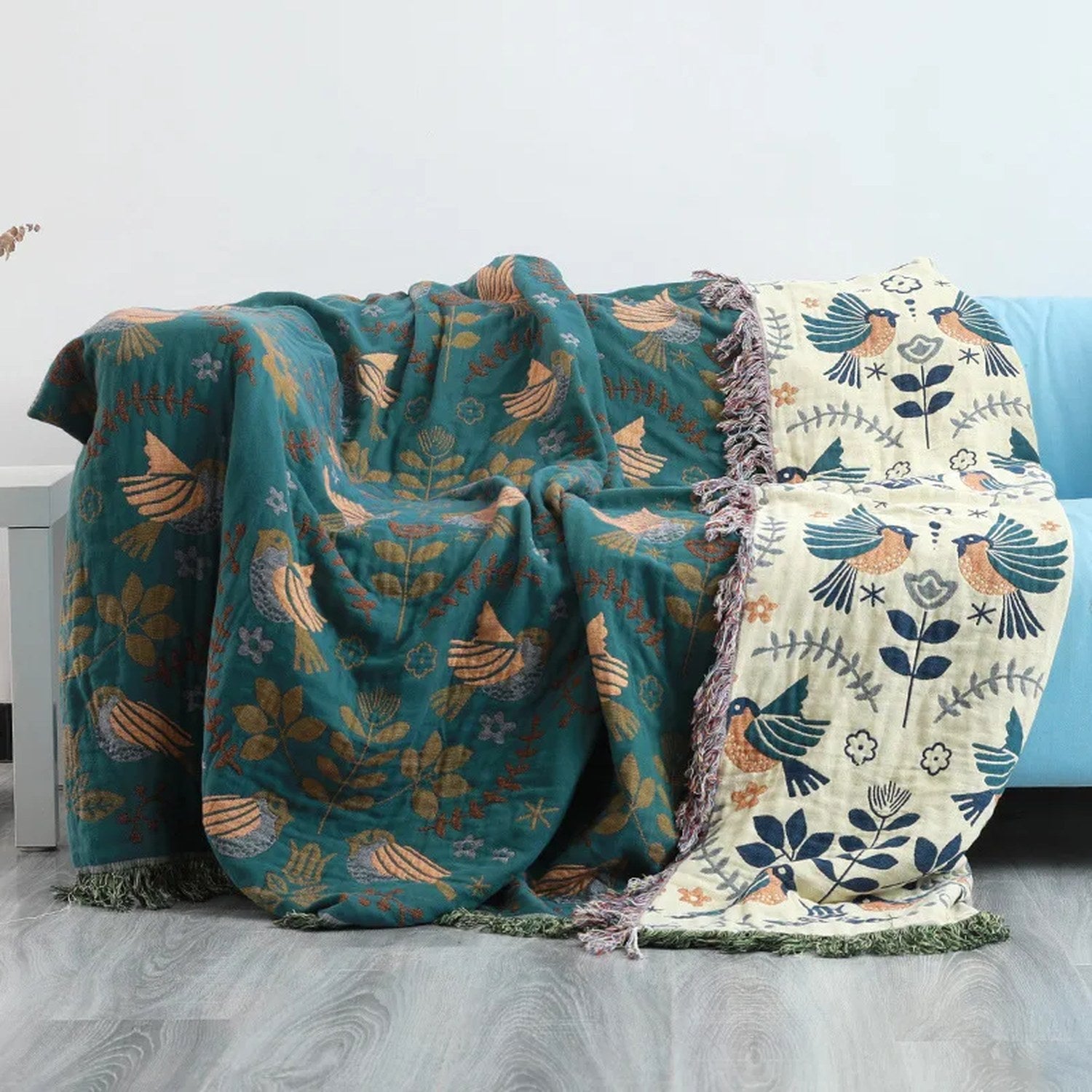 Plaid bohème gaze de coton turquoise foncé motifs oiseaux drapé sur un canapé bleu