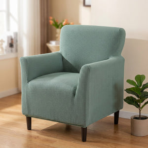 Fauteuil habillé d'une housse jacquard vert sauge dans un salon lumineux
