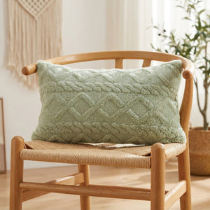 Housse de coussin lombaire en peluche vert sauge à relief géométrique sur un fauteuil en bois