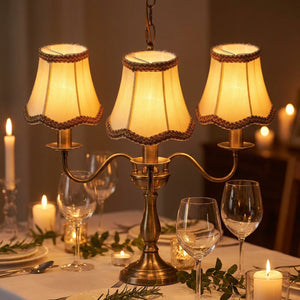 Lustre bougie avec 3 abat-jours tissu blanc crème au-dessus d'une table à dîner