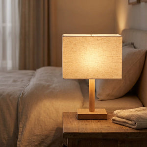 Abat-jour en lin beige sur une lampe de chevet allumée dans une chambre cosy