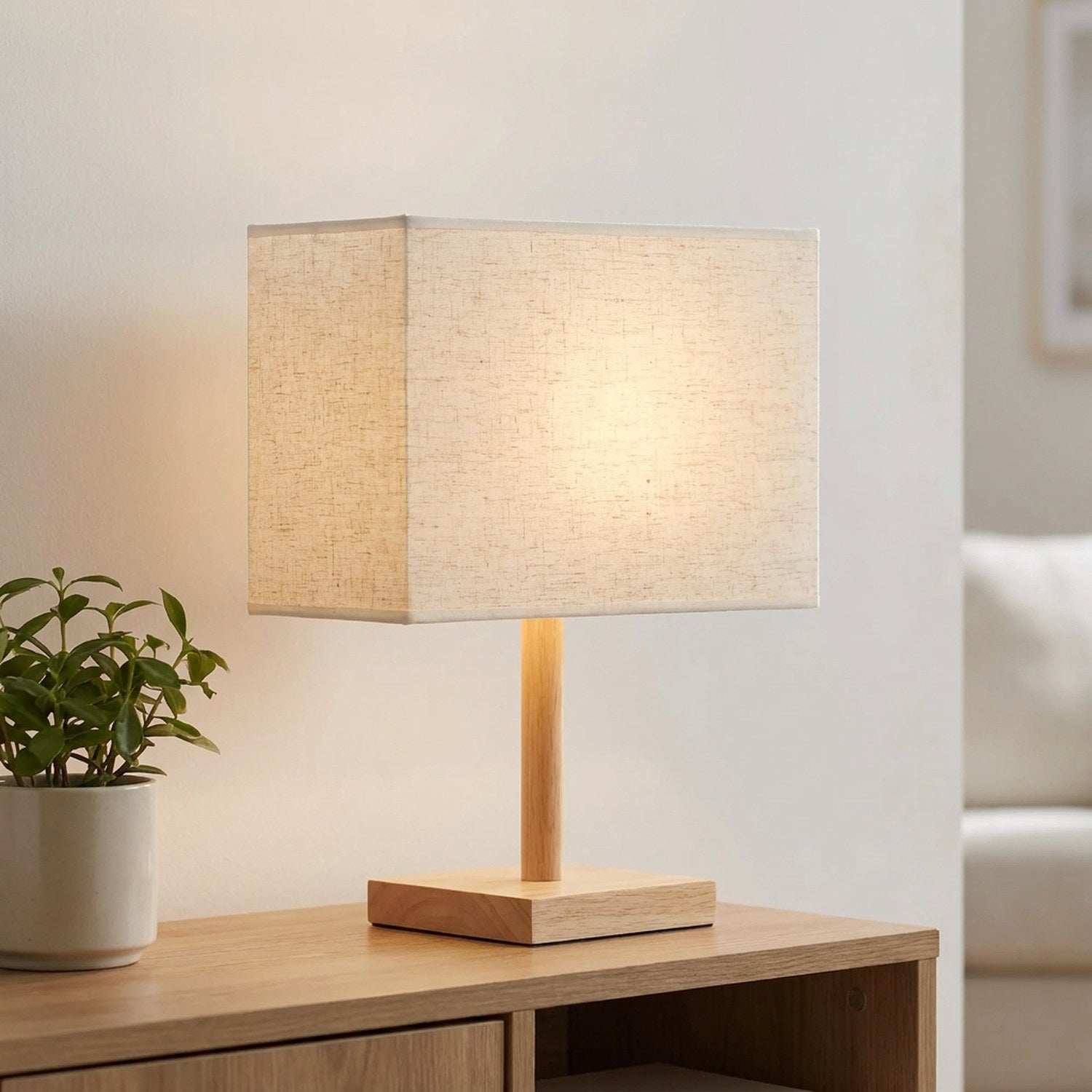 Abat-jour rectangulaire en lin beige sur une console avec une plante en journée