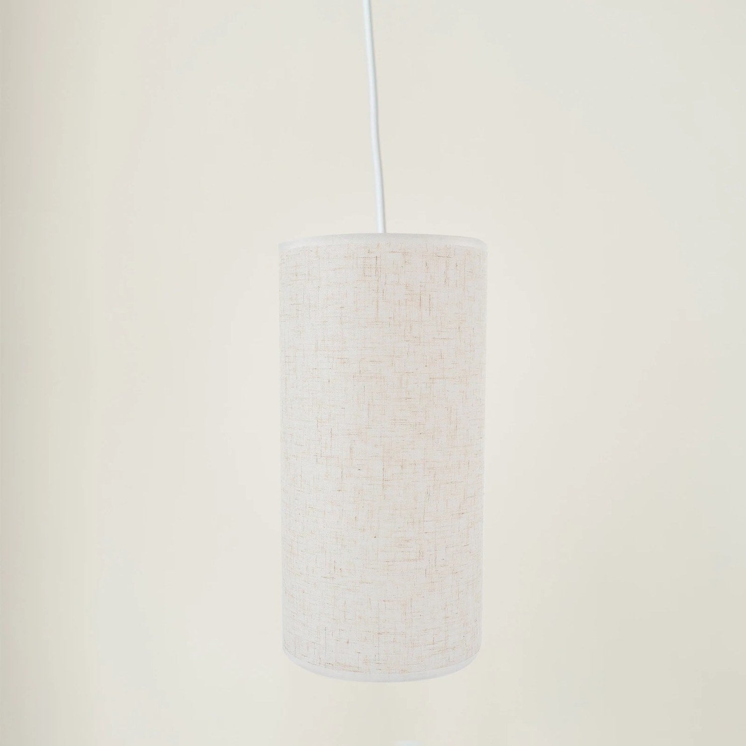 Abat-jour tambour en lin suspendu sur fond neutre