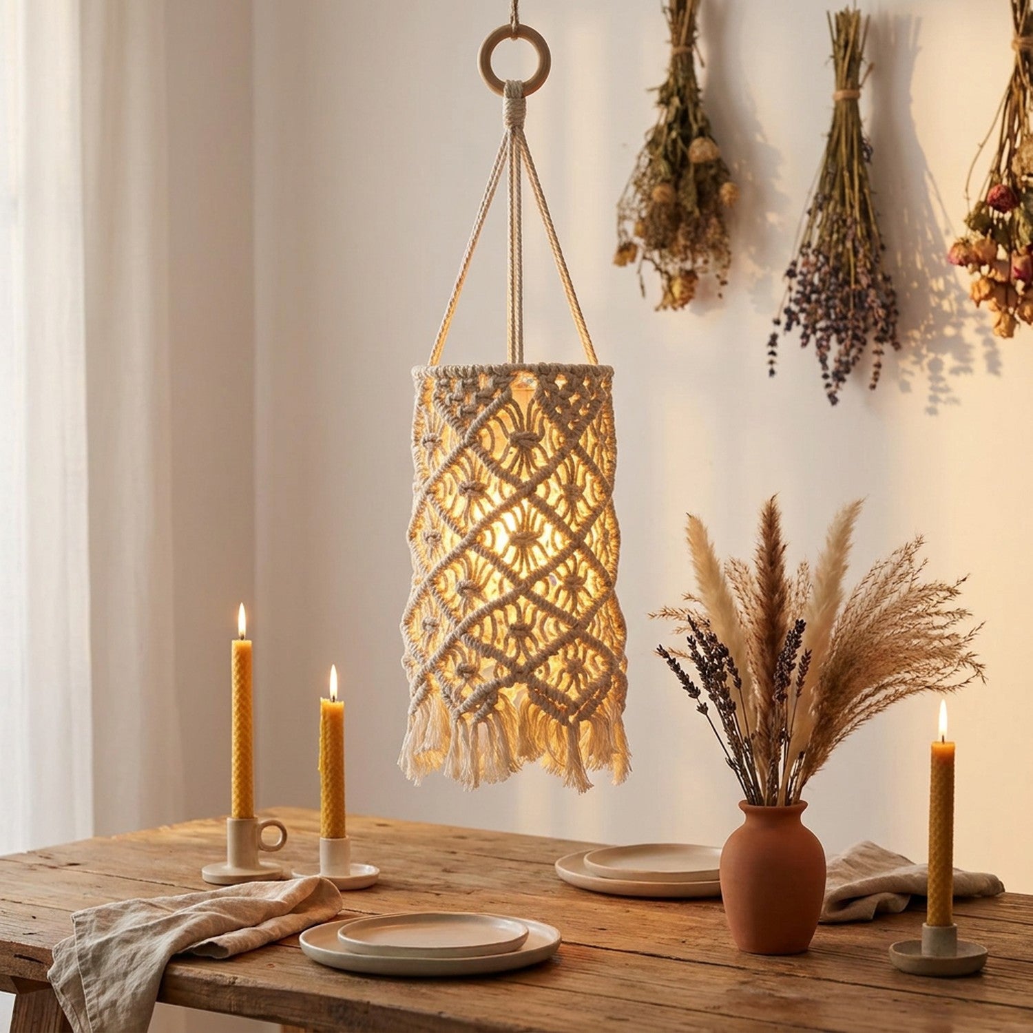 Abat-jour macramé suspendu au-dessus d'une table en bois avec bougies et fleurs séchées
