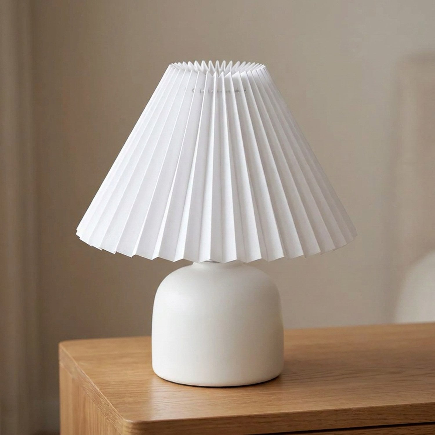 Abat-jour plissé conique en tissu blanc sur une lampe allumée