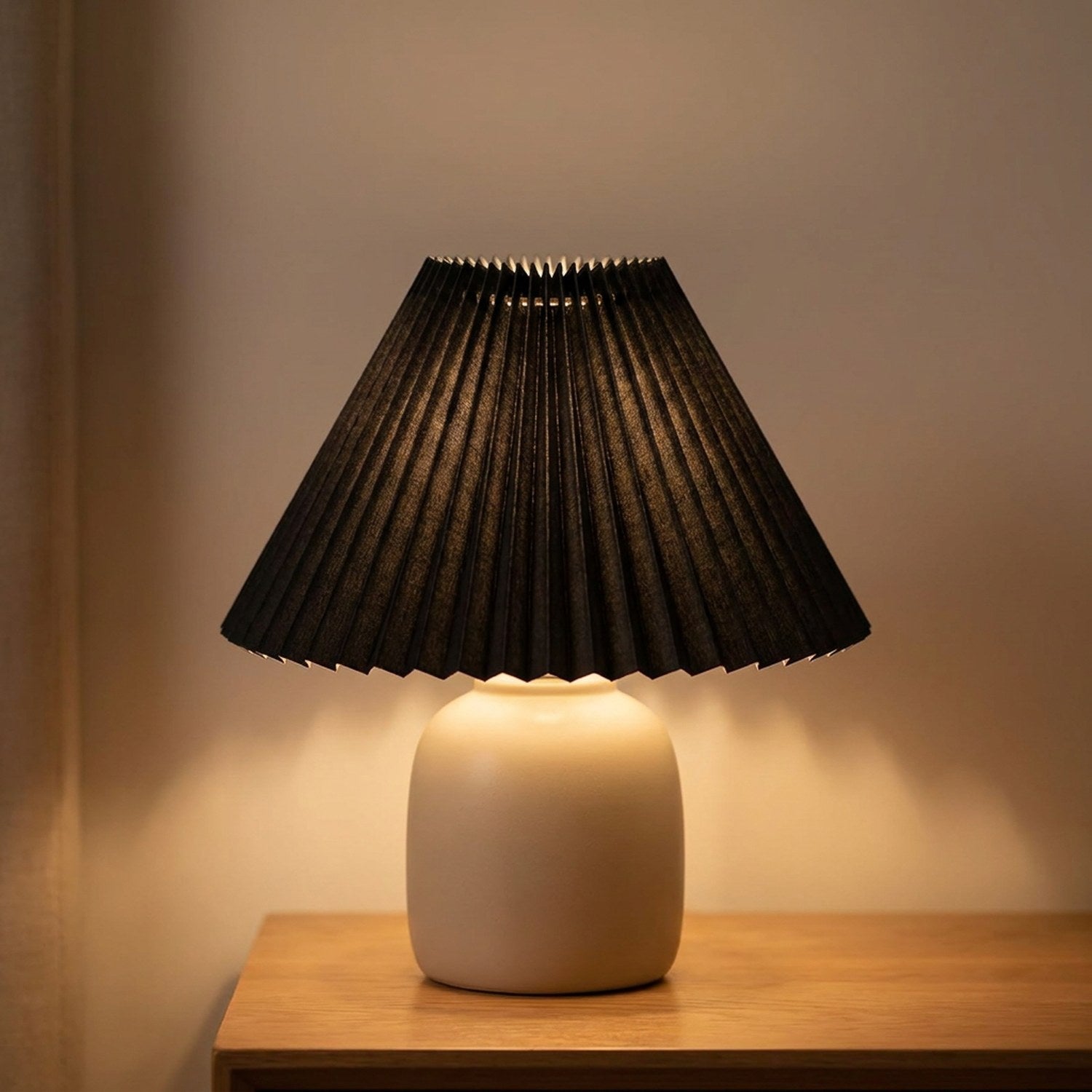 Abat-jour plissé conique en tissu coloris Noir sur une lampe allumée