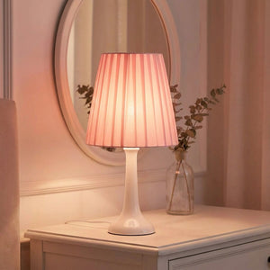 Abat-jour plissé rose sur coiffeuse dans une chambre romantique