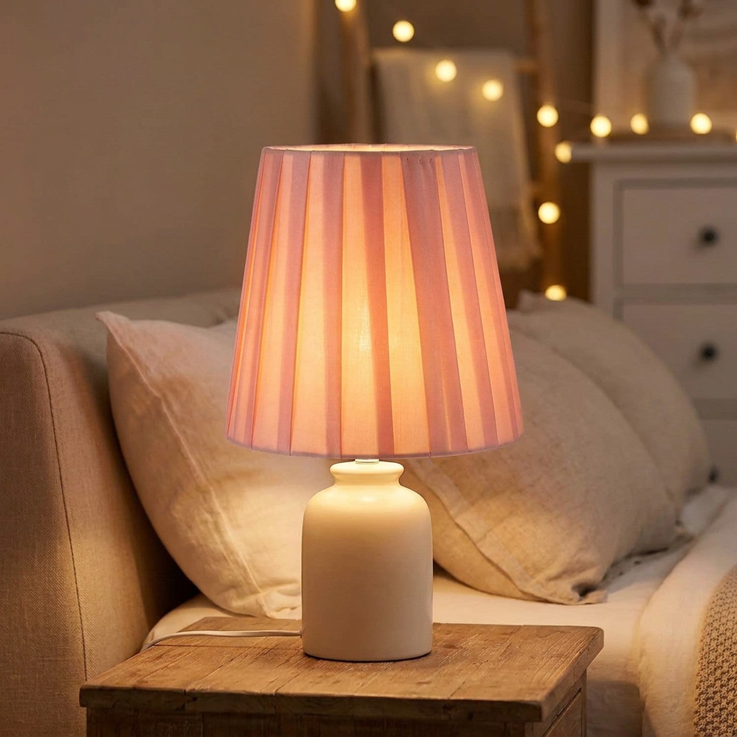 Abat-jour plissé en tissu rose sur lampe de table dans une chambre chaleureuse