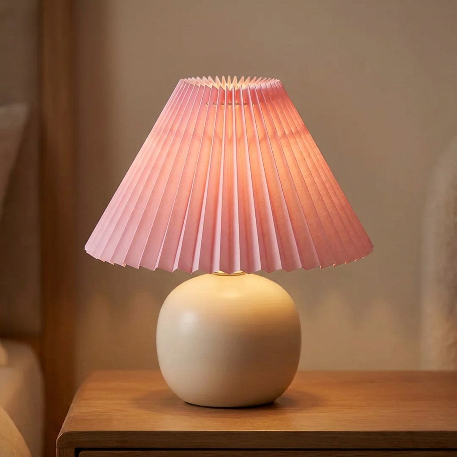 Abat-jour plissé conique en tissu coloris Rose sur une lampe allumée