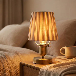 Abat-jour à clipser beige en tissu plissé sur une lampe de table dans une chambre chaleureuse