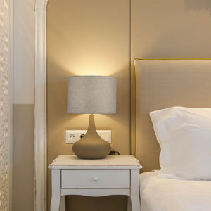 Abat-jour tambour en lin gris sur lampe de chevet céramique dans chambre chaleureux