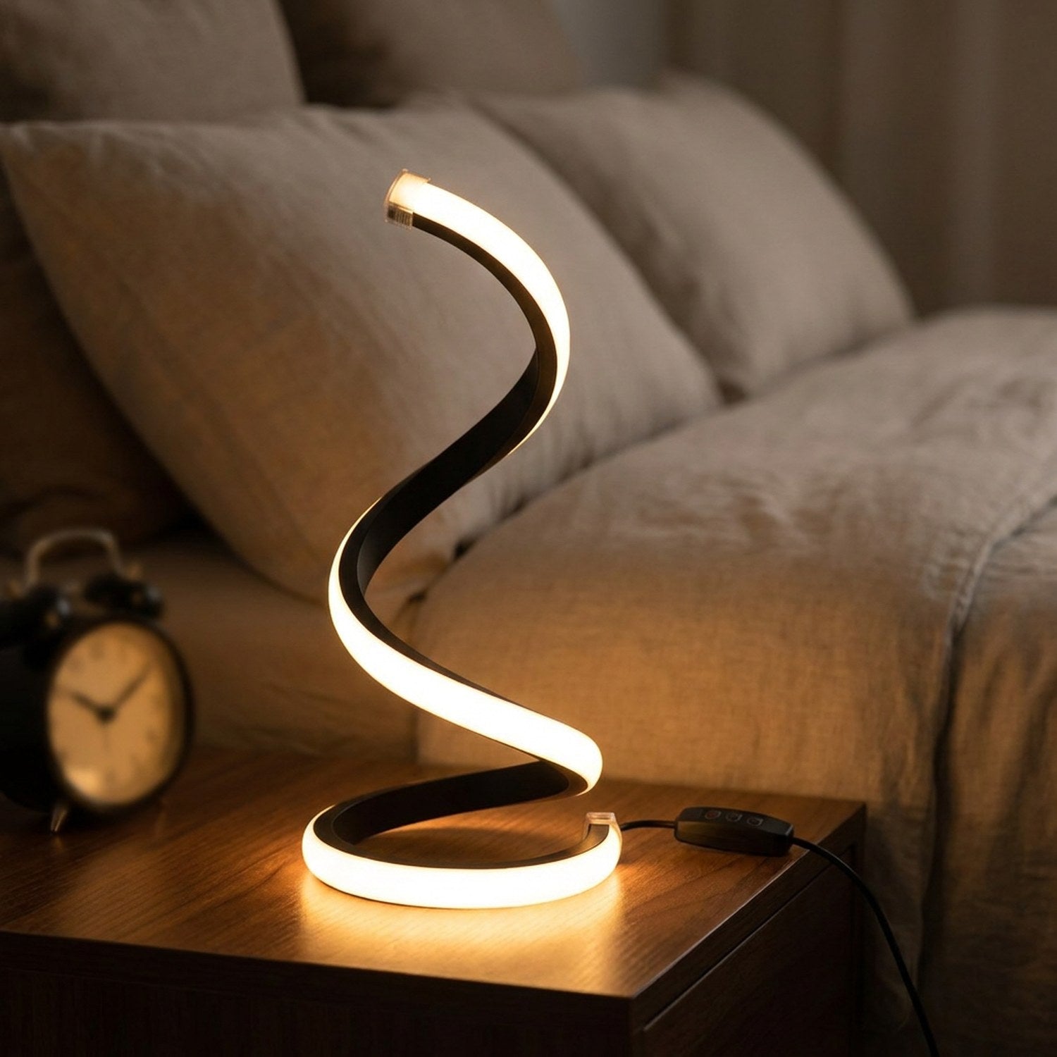 Lampe spirale LED allumée sur une table de chevet près d'un lit avec réveil