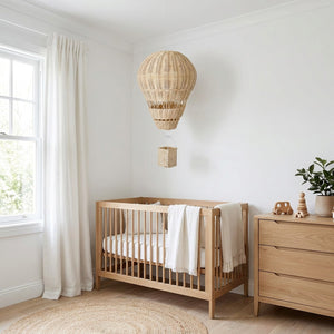 Ballon à air chaud en rotin naturel suspendu dans une nursery scandinave lumineuse