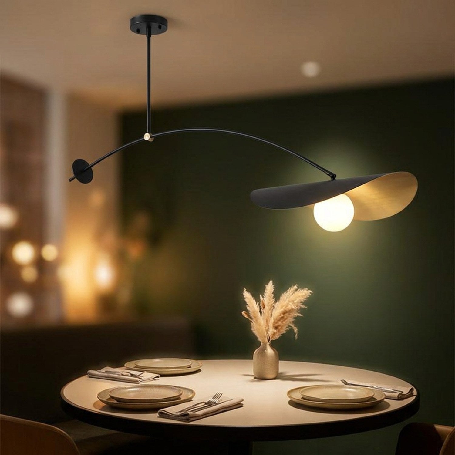 Suspension design éclairant une table ronde dressée dans une salle à manger aux murs verts