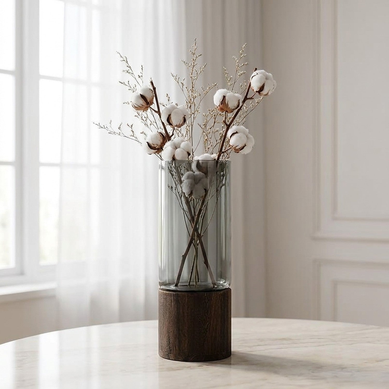 Vase cylindrique en verre fumé sur surface marbre avec fleurs de coton près d une fenêtre