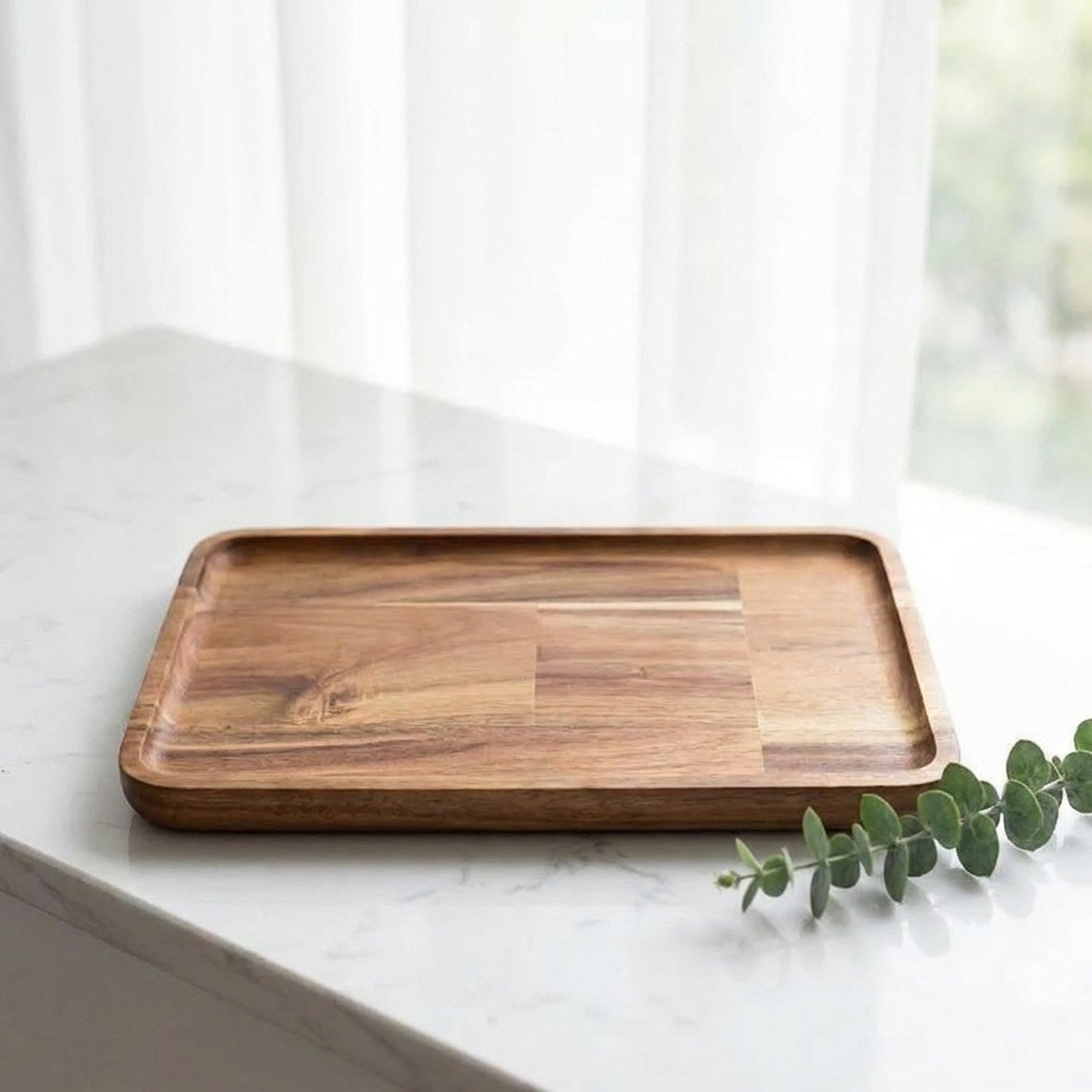 Plateau de service bois acacia sur surface marbre avec feuille d'eucalyptus