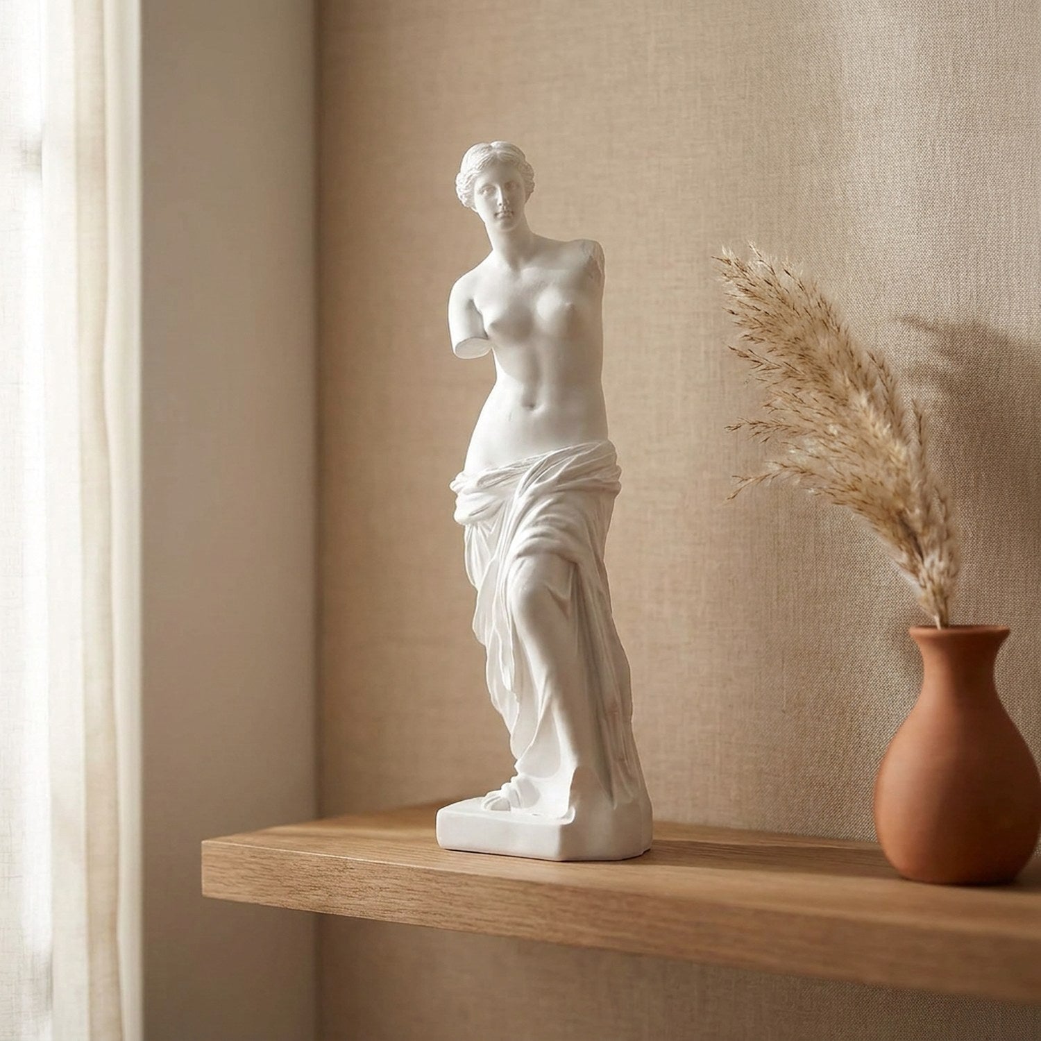 Sculpture Vénus de Milo sur une étagère flottante en bois avec vase terracotta et herbes de pampa