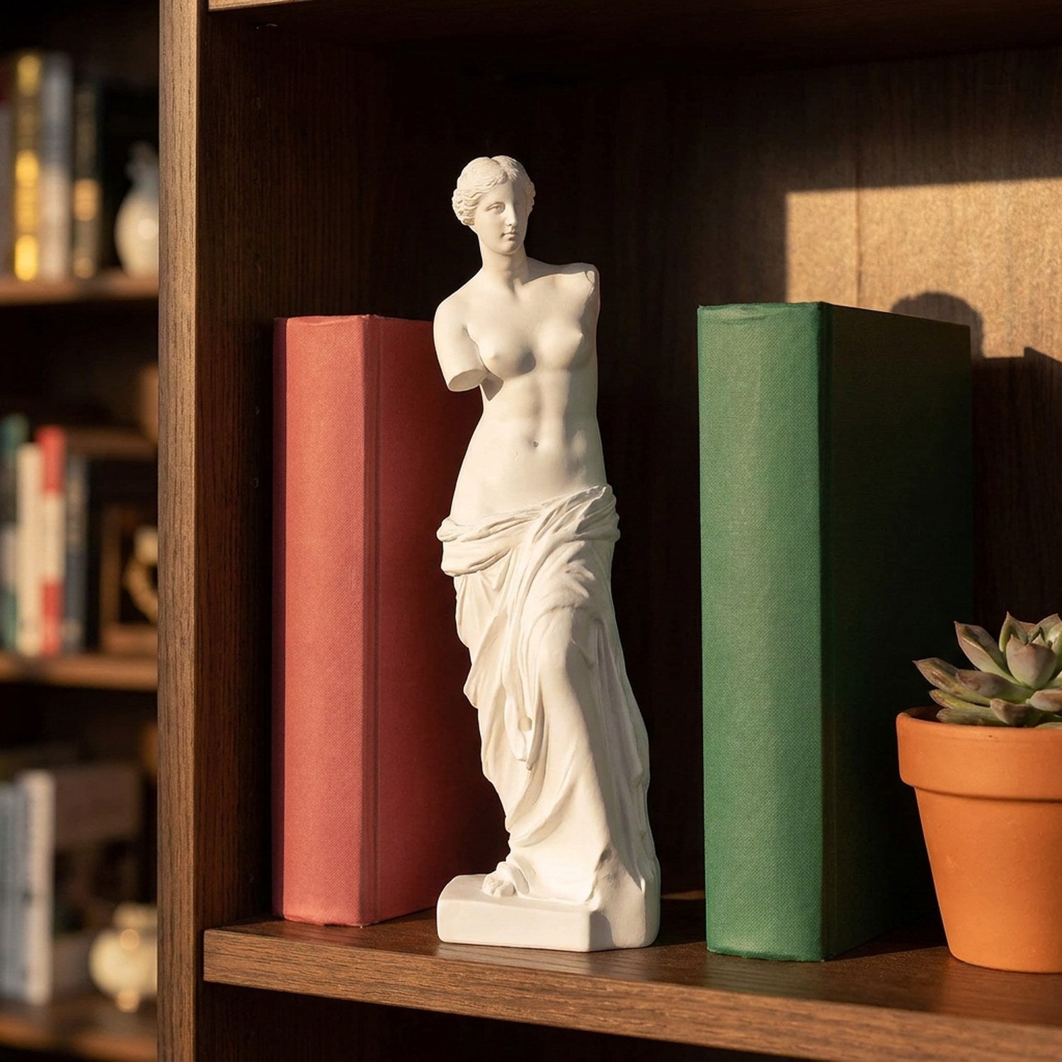 Sculpture Vénus de Milo entre deux livres colorés sur une étagère en bois avec lumière dorée
