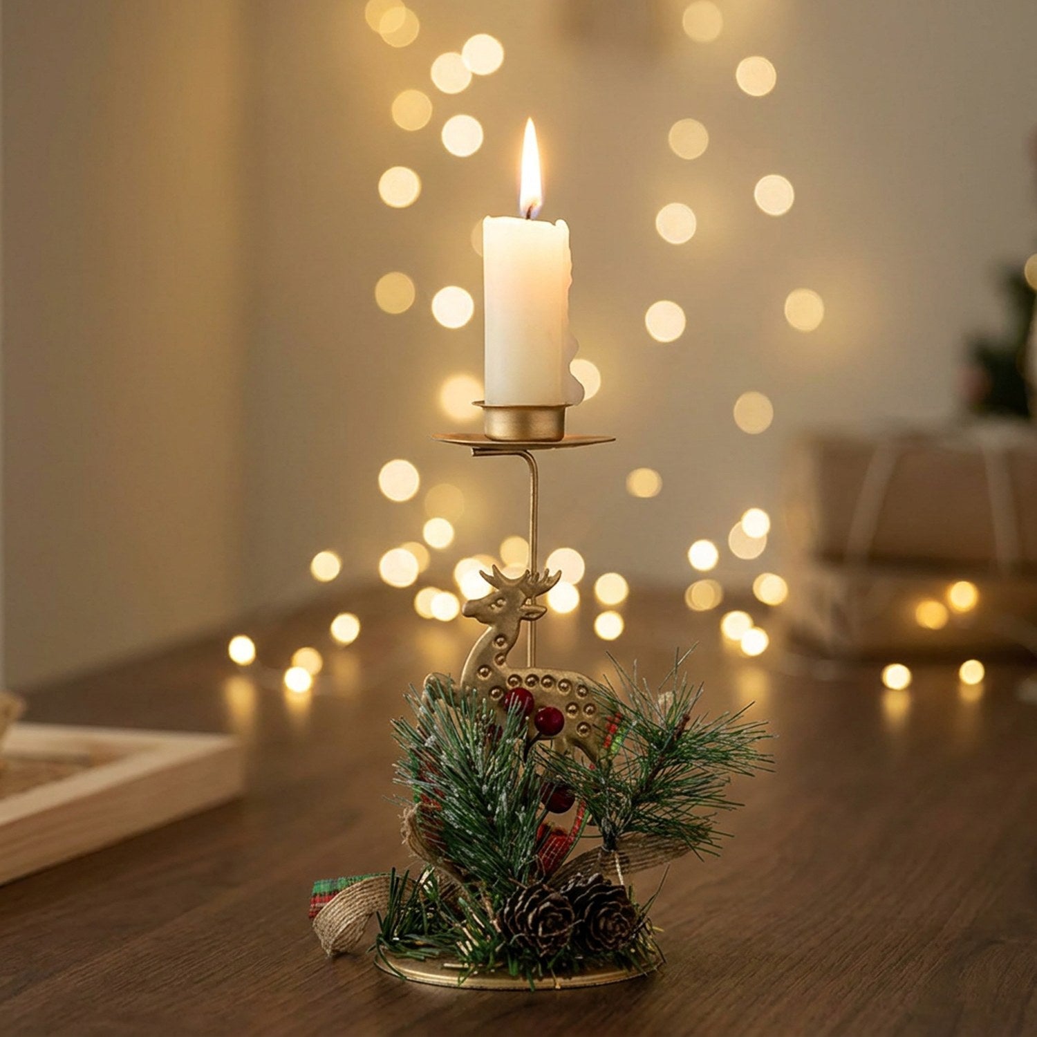 Bougeoir de Noël en fer doré avec renne et décoration naturelle posé sur une table festive avec bougie allumée
