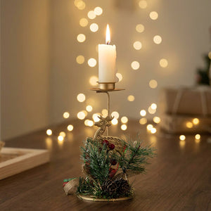 Bougeoir de Noël en fer doré avec renne et décoration naturelle posé sur une table festive avec bougie allumée