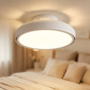 Plafonnier LED blanc sans pale fixé au plafond d'une chambre avec lumière douce allumée et effet bokeh