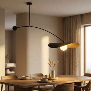 Suspension nordique noire et dorée au bras arqué éclairant une table à manger au coucher du soleil