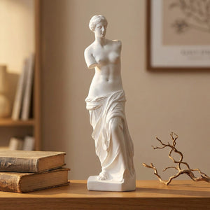 Sculpture Vénus de Milo en résine blanche posée sur une console en bois avec livres anciens