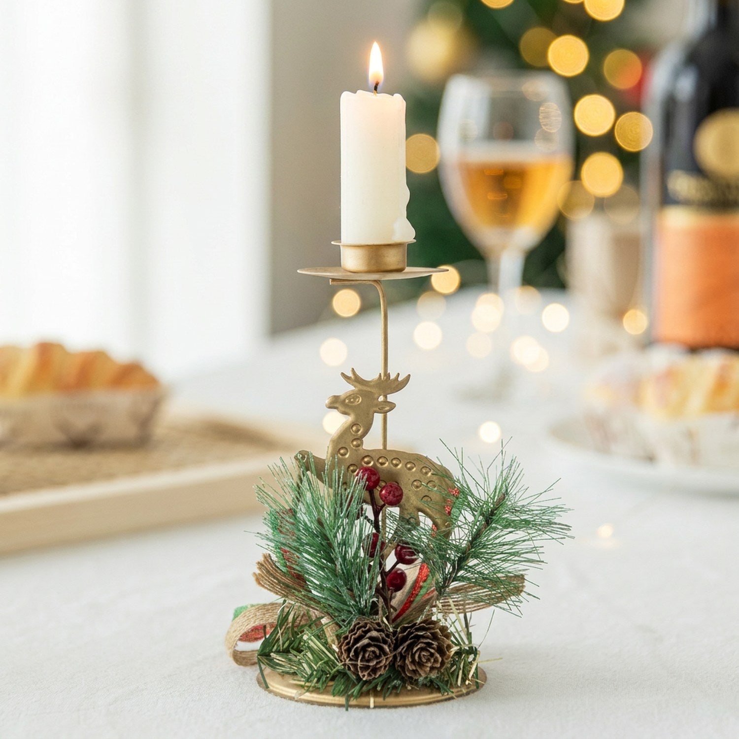 Bougeoir de Noël modèle Renne en fer doré avec branches de pin et baies rouges bougie allumée sur table