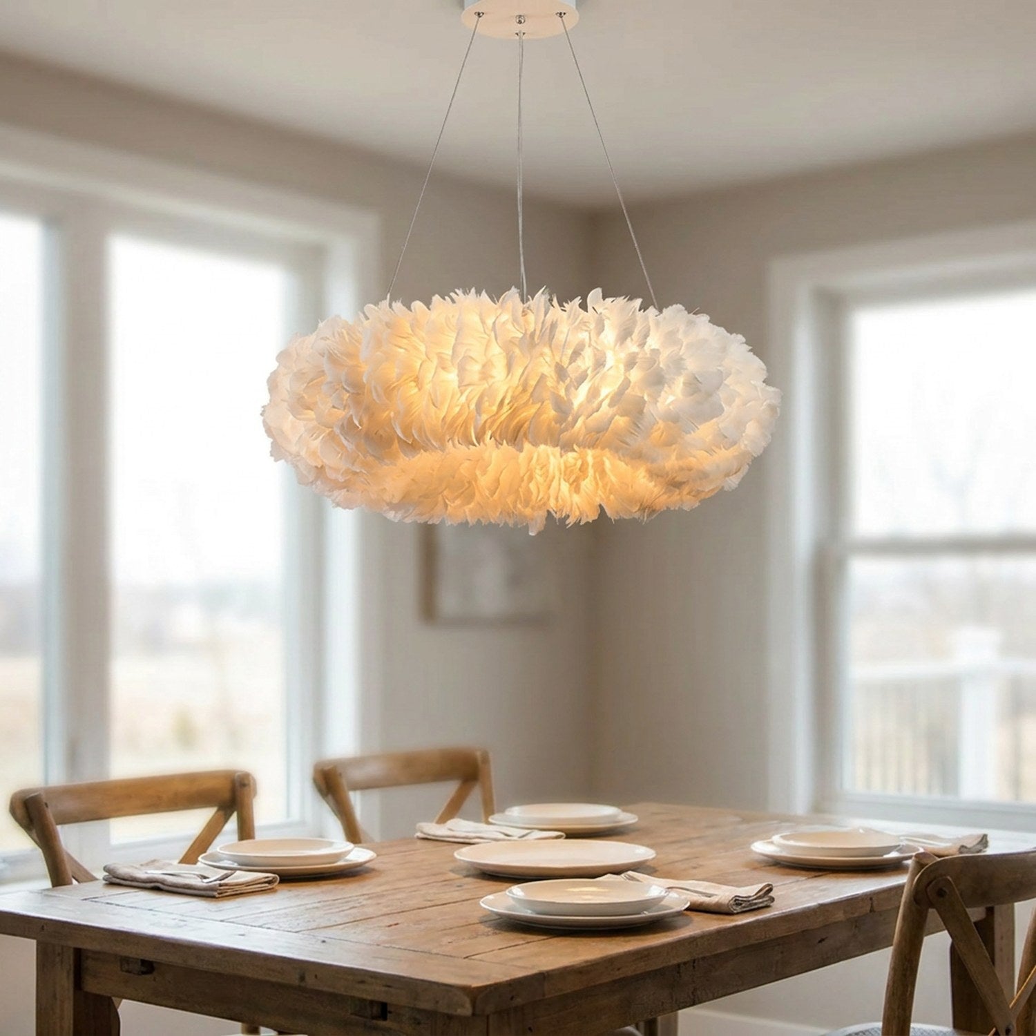Lustre suspension en plumes blanches allumé au-dessus d'une table à manger en bois