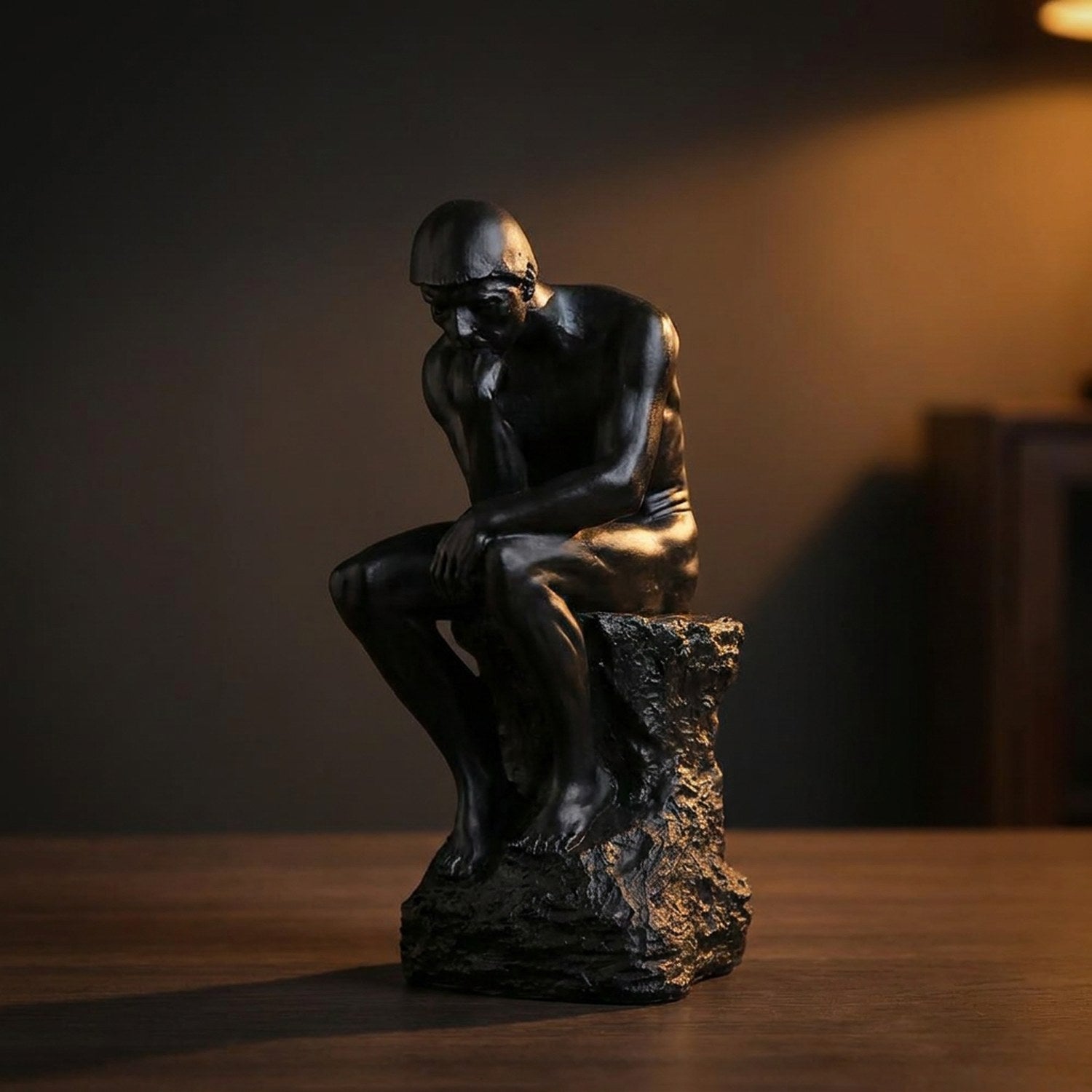 Statue penseur de Rodin en résine noire sur table bureau en bois lumière dramatique