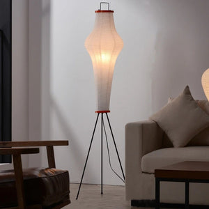 Lampadaire Akari japonais allumé dans un salon avec canapé et fauteuil bois