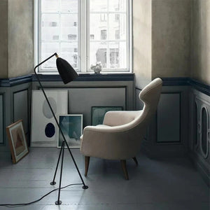 Lampadaire trépied noir dans un salon scandinave près d'un fauteuil beige