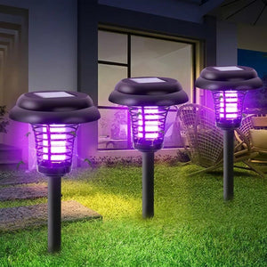 Trois lampes anti-moustiques solaires allumées dans un jardin la nuit