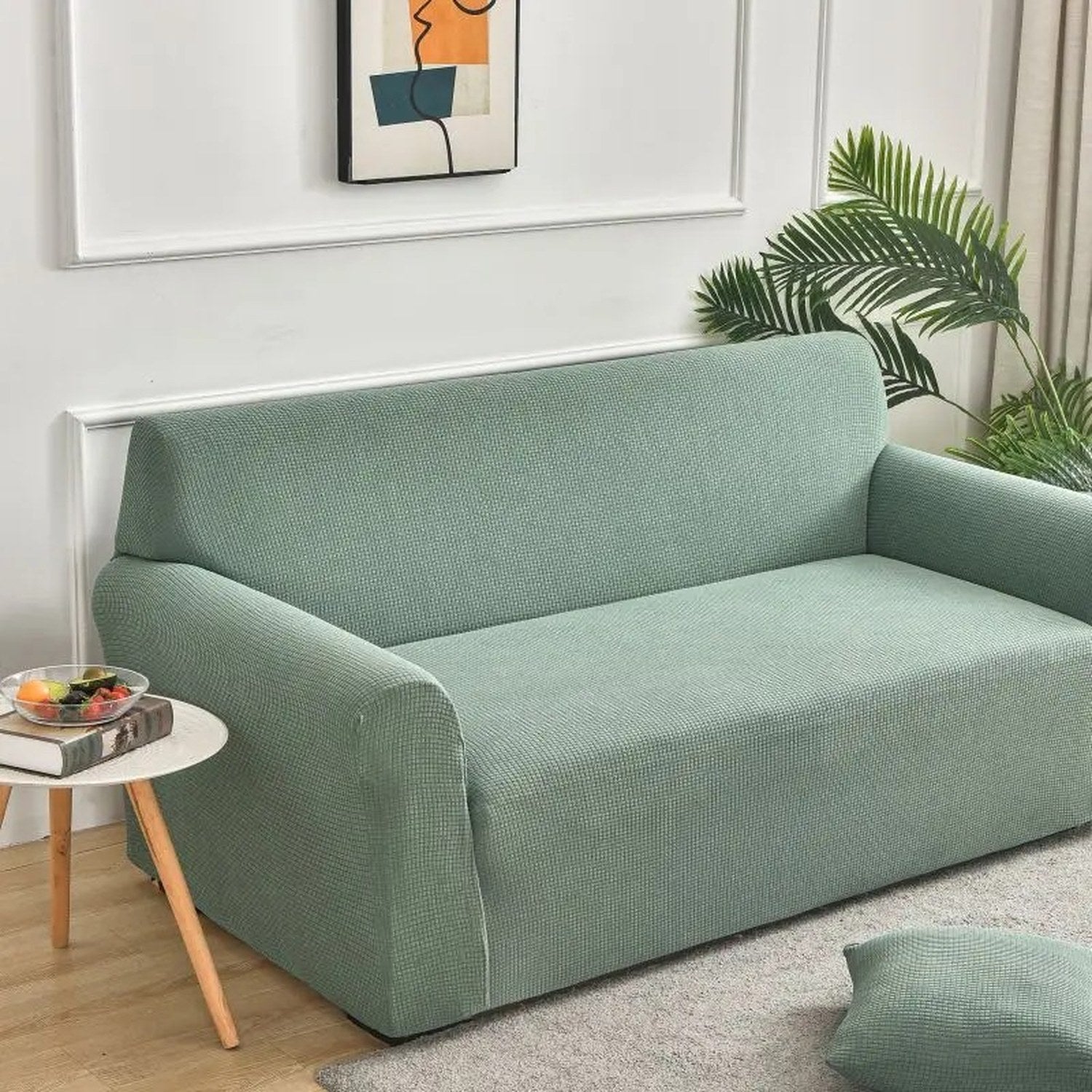 Housse de canapé en velours vert sauge dans un salon avec plante verte