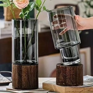 Vase en verre fumé avec base en bois avec roses roses en intérieur chaleureux