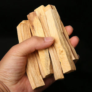Main tenant des bâtons d'encens Palo Santo naturels sur fond sombre