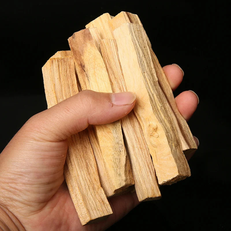 Main tenant des bâtons d'encens Palo Santo naturels sur fond sombre