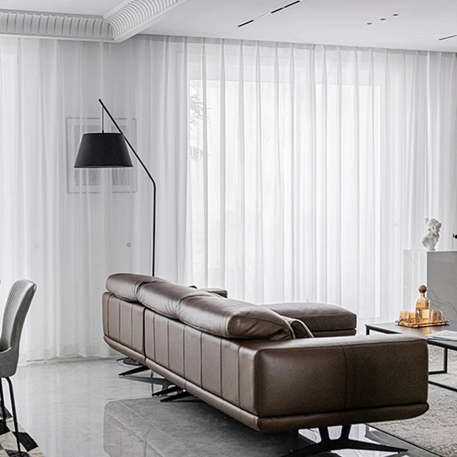Voilage blanc en tulle transparent le long d'une grande baie vitrée de salon