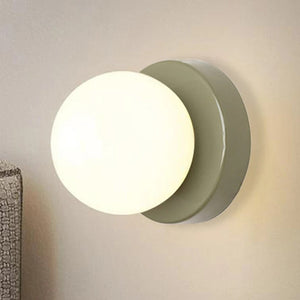 Applique murale beige avec globe en verre allumé près d'une tête de lit