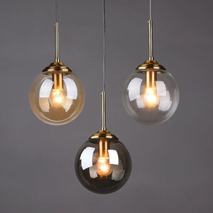 Suspension globe en verre design nordique disponible en 3 teintes ambre transparent fume gris monture laiton dore
