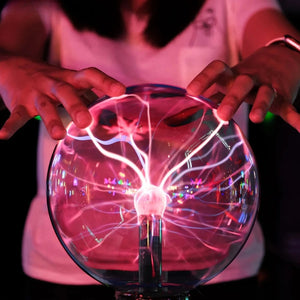 Mains posées sur une lampe boule de plasma avec éclairs lumineux roses et violets
