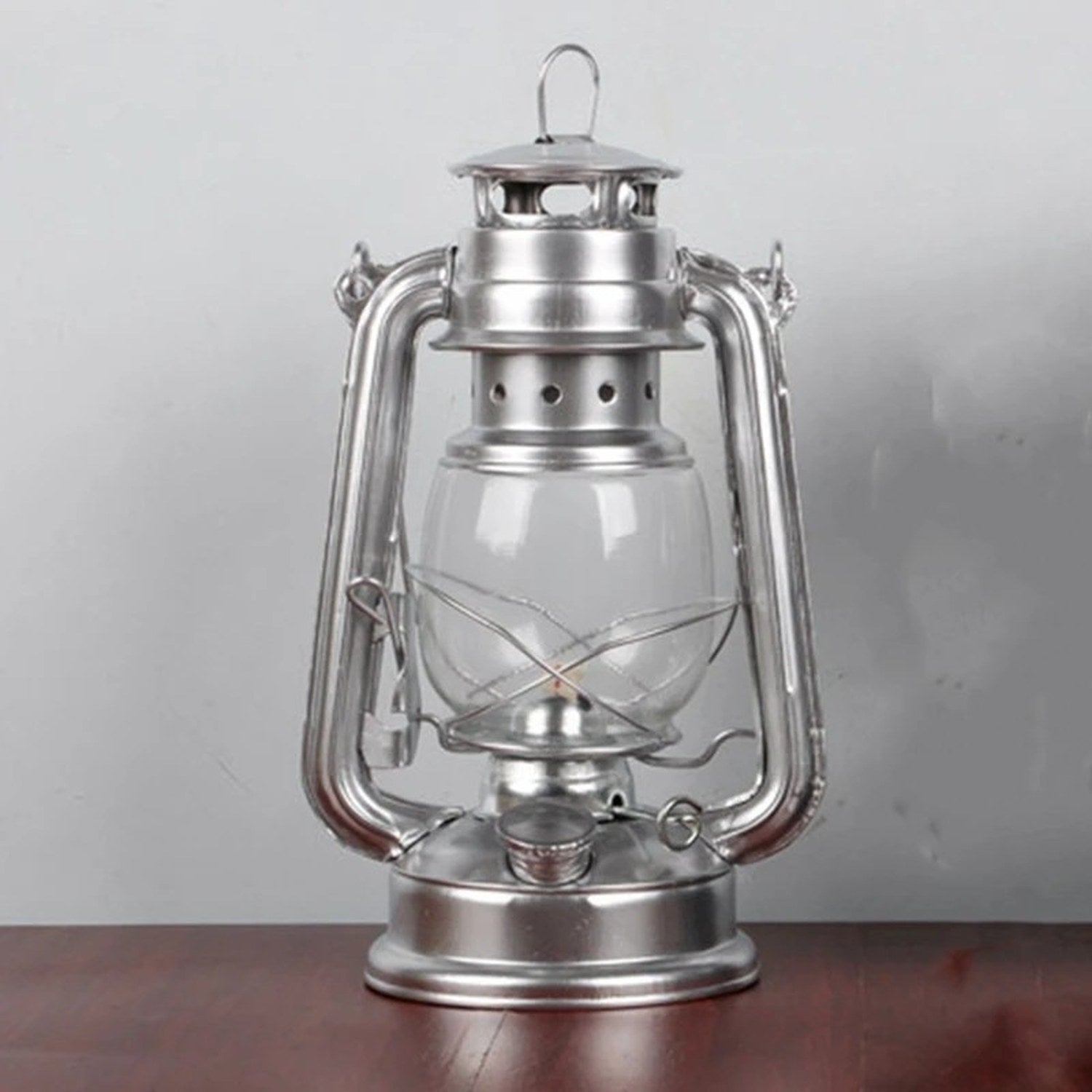 Lanterne tempête vintage en fer argenté avec globe en verre sur une table en bois