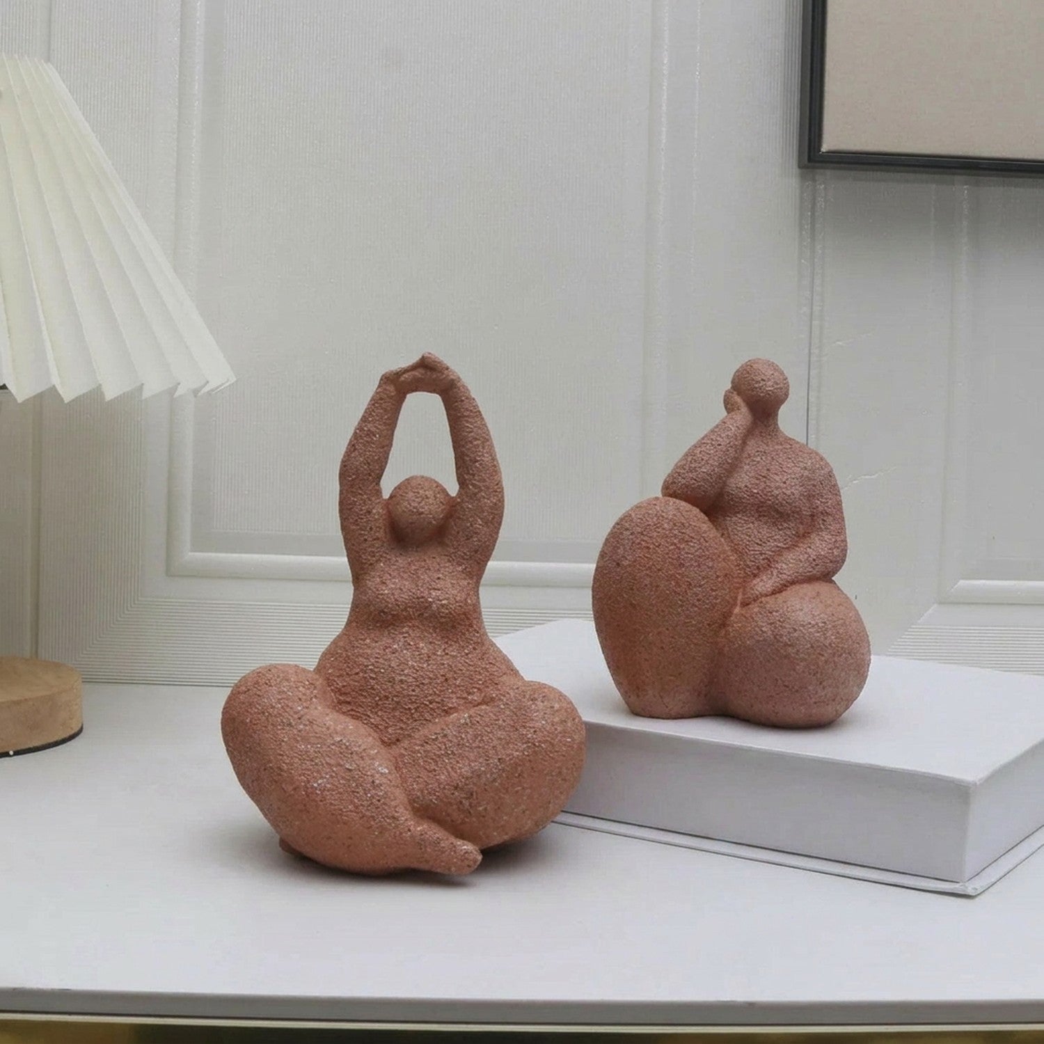 Statuette femme yoga et statuette femme pensive en résine sableuse sur console blanche