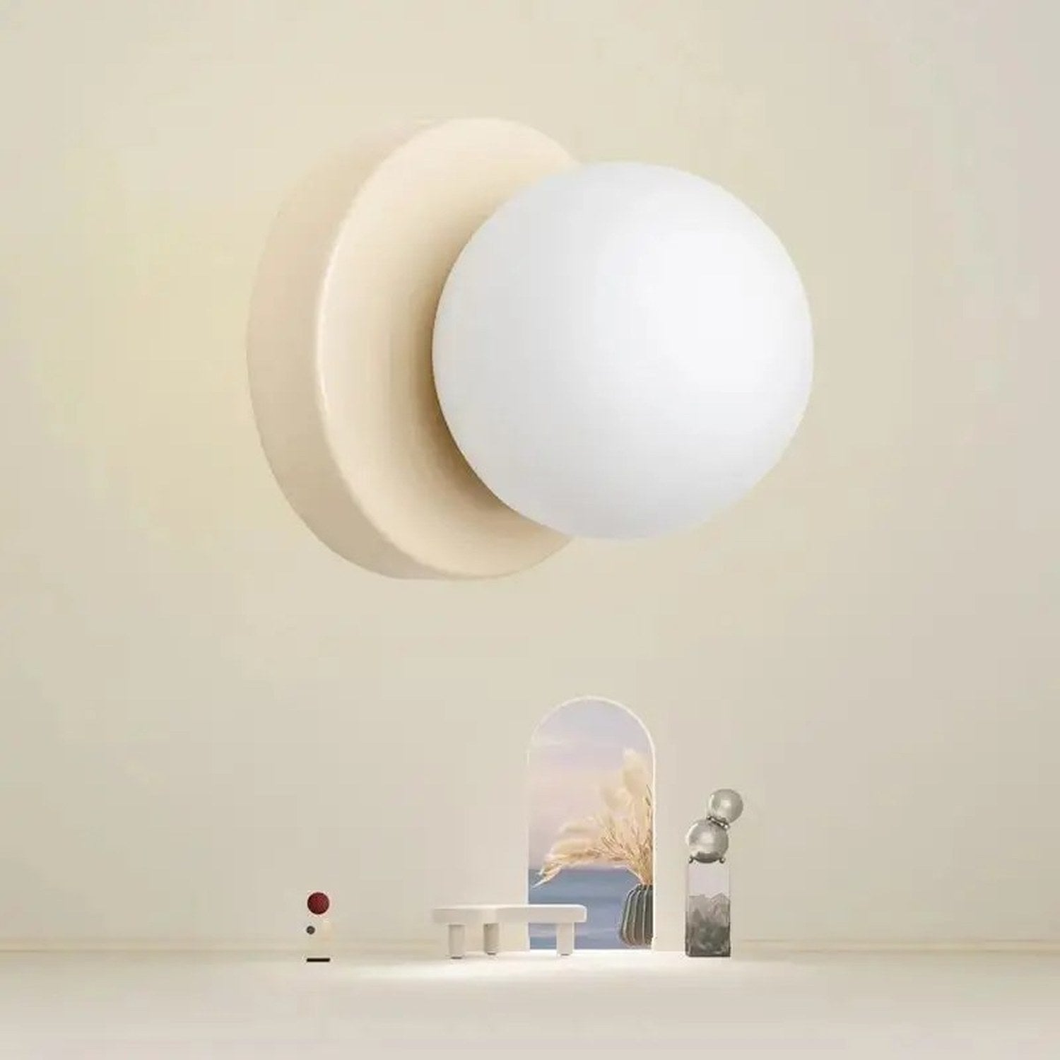 Applique murale forme boule en verre sur fond beige avec objets de décoration