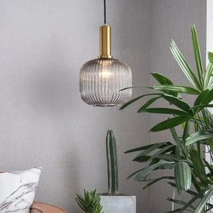 Suspension en verre vert texturé et laiton doré près d'une plante d'intérieur