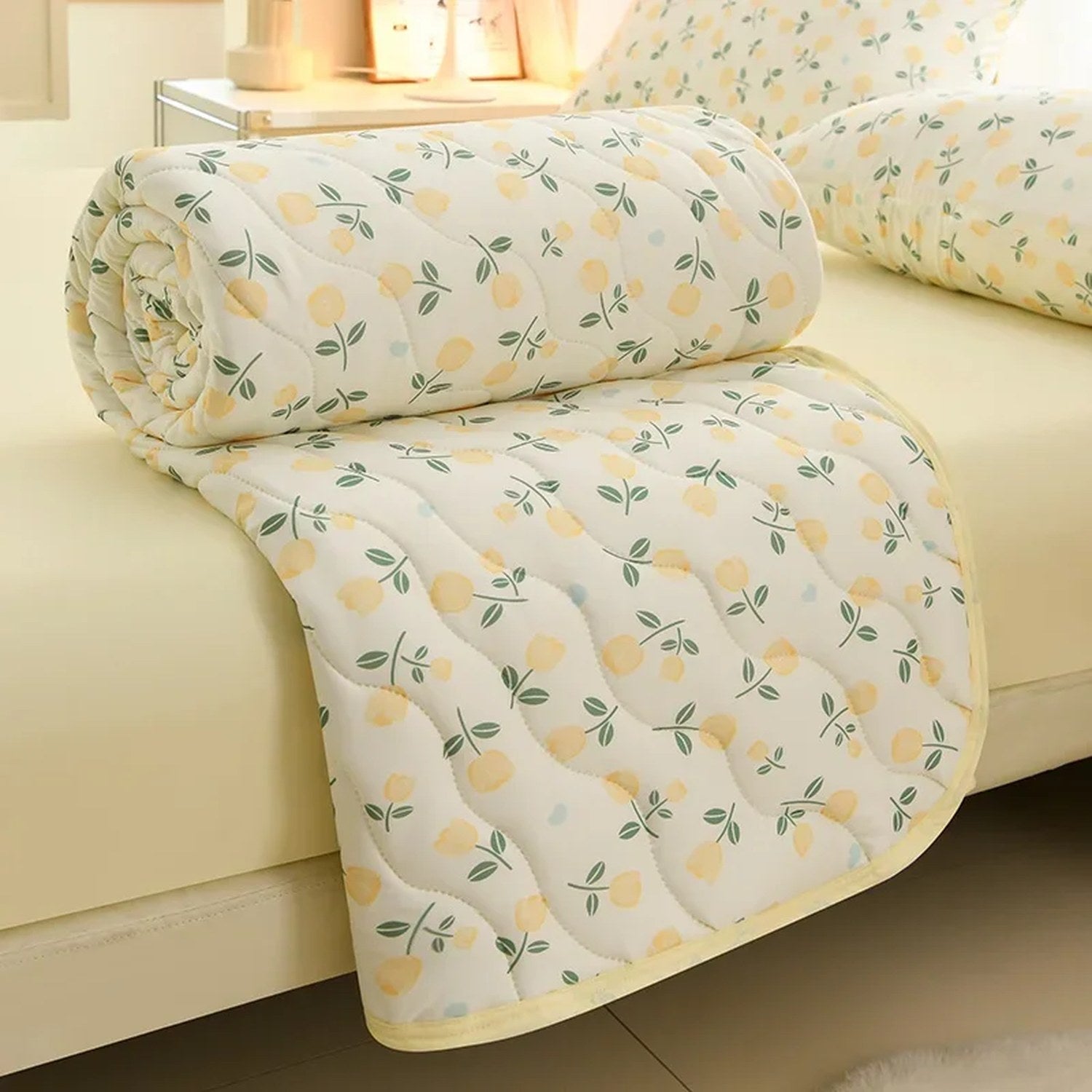 Couette matelassée à imprimé fleuri jaune roulée sur un lit