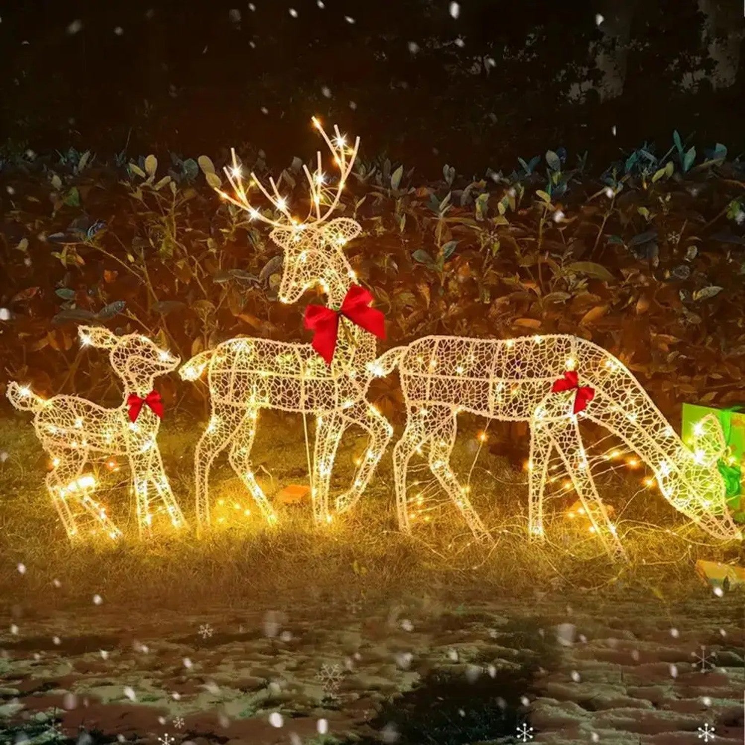 Rennes lumineux de Noël en métal LED dans un jardin enneigé la nuit